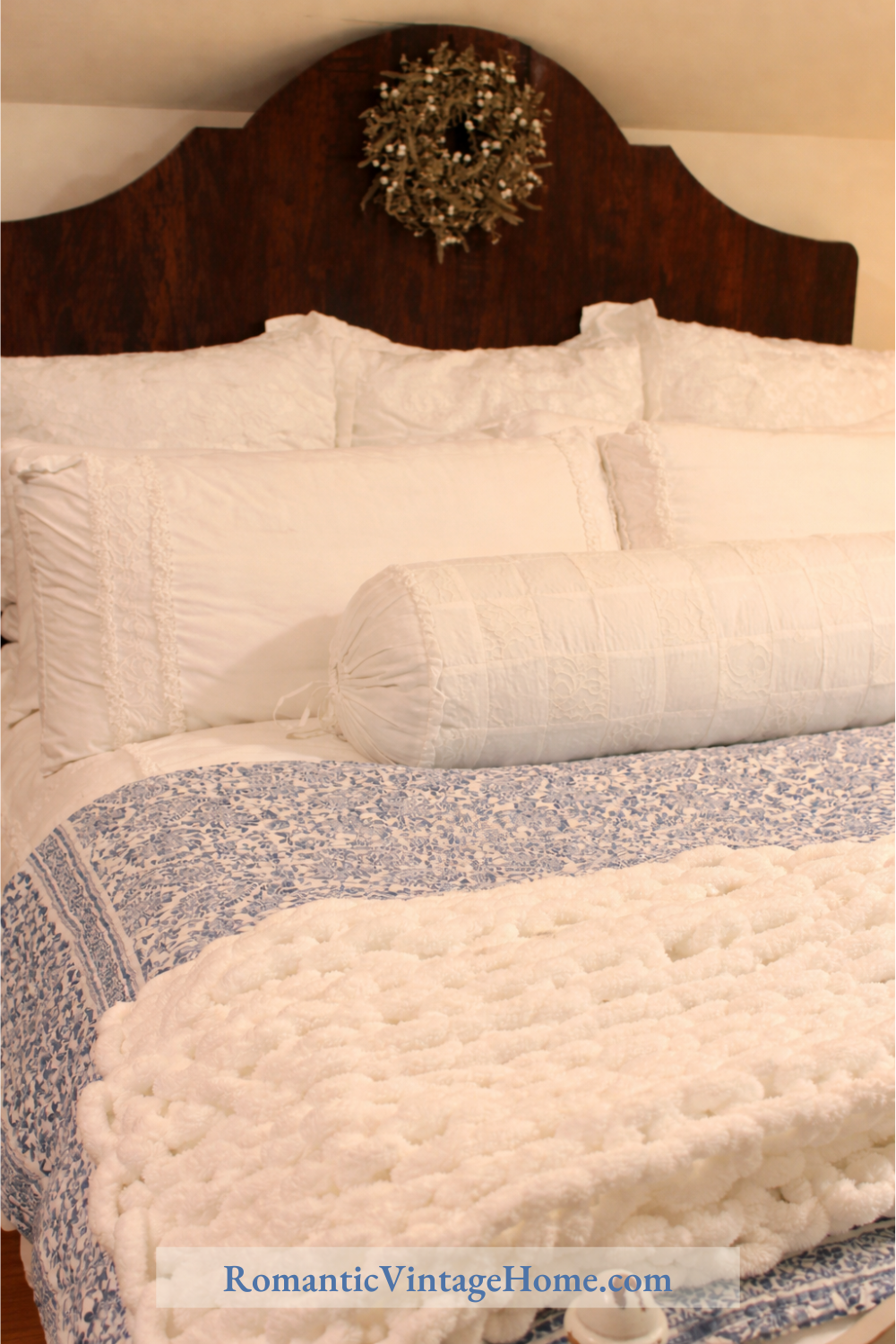 Cozy guest bedroom with layered white bedding, a blue-and-white floral quilt, and soft vintage-inspired textures